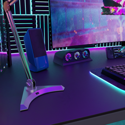 Blue computer speaker with neon lighting on a dark desk, gaming or tech setup with colorful LED accents, illuminated gauges, and monitor displaying a vibrant digital background for a modern tech environment.